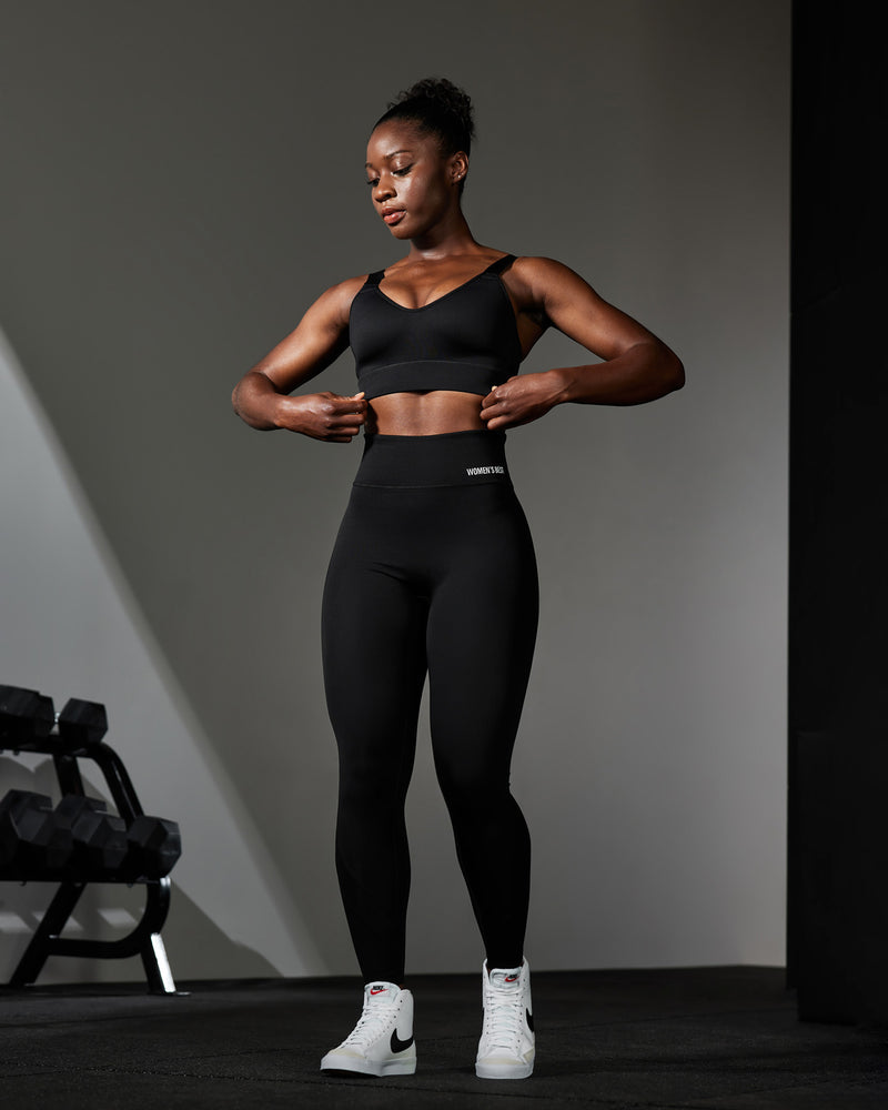 A woman wearing tight shorts and a sports crop top holding weights